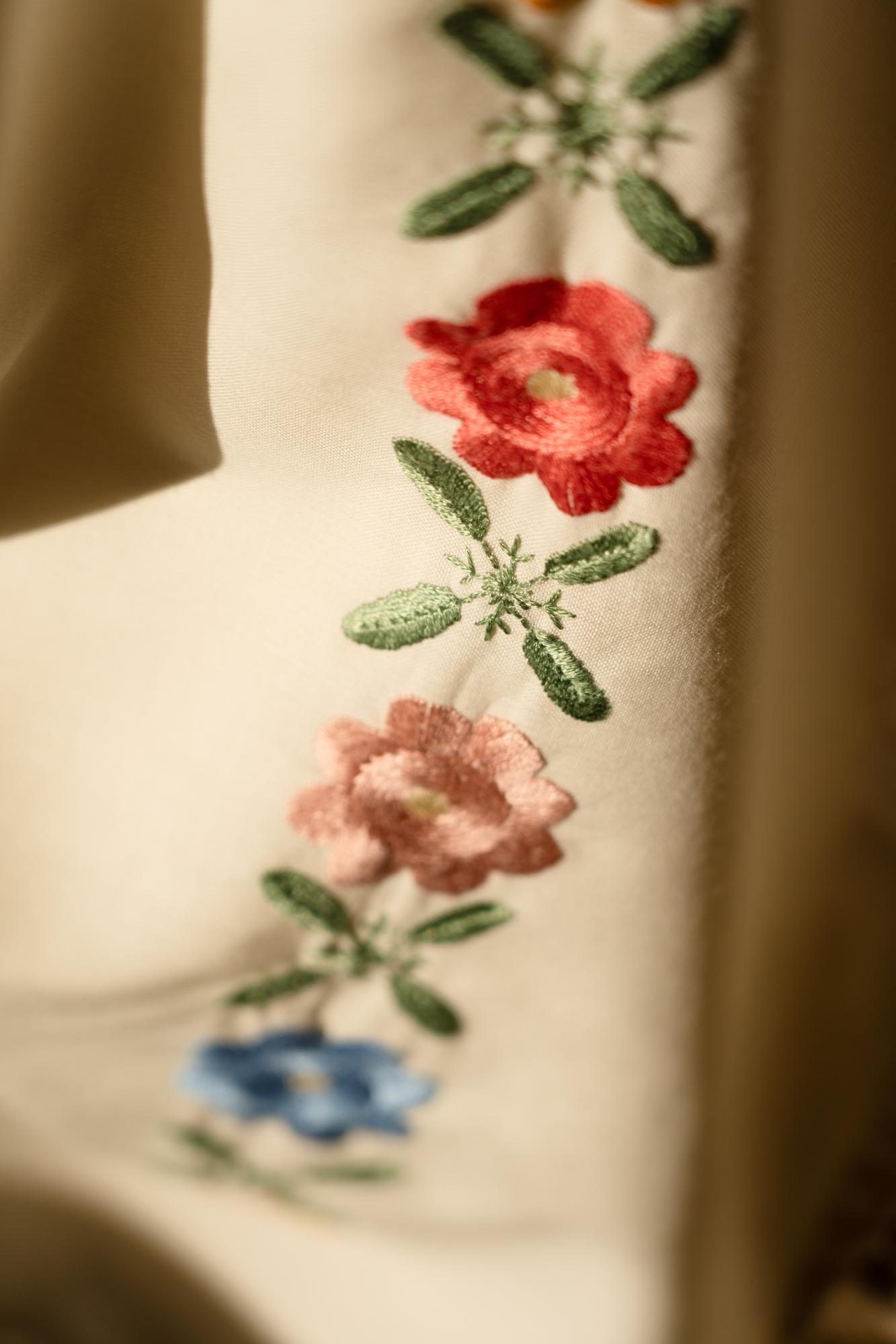 Close-up of hand embroidering floral motif on linen
